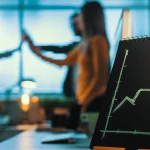 Gráfico de crecimiento empresarial con flecha ascendente en una oficina con un equipo de trabajo celebrando al fondo.